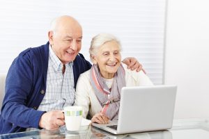 Happy senior citizen couple using laptop computer at home